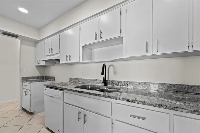 a kitchen with granite countertop white cabinets and white appliances
