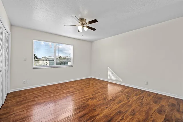 a view of an empty room with window and wooden floor