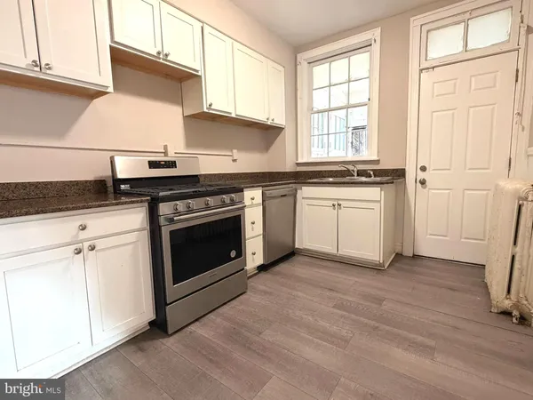 a kitchen with granite countertop stainless steel appliances a stove top oven and sink