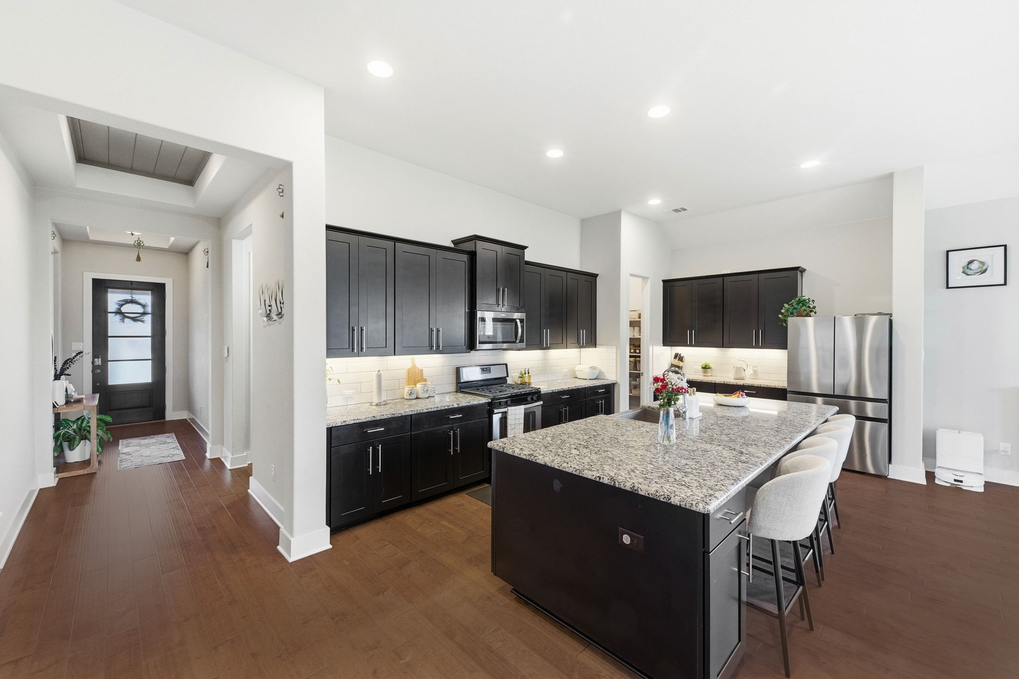 108 Leon Loop Liberty Hill, TX 78642 - Photo 14 of 39 Kitchen with light stone countertops, appliances with stainless steel finishes, dark cabinetry, tasteful backsplash, and a breakfast bar