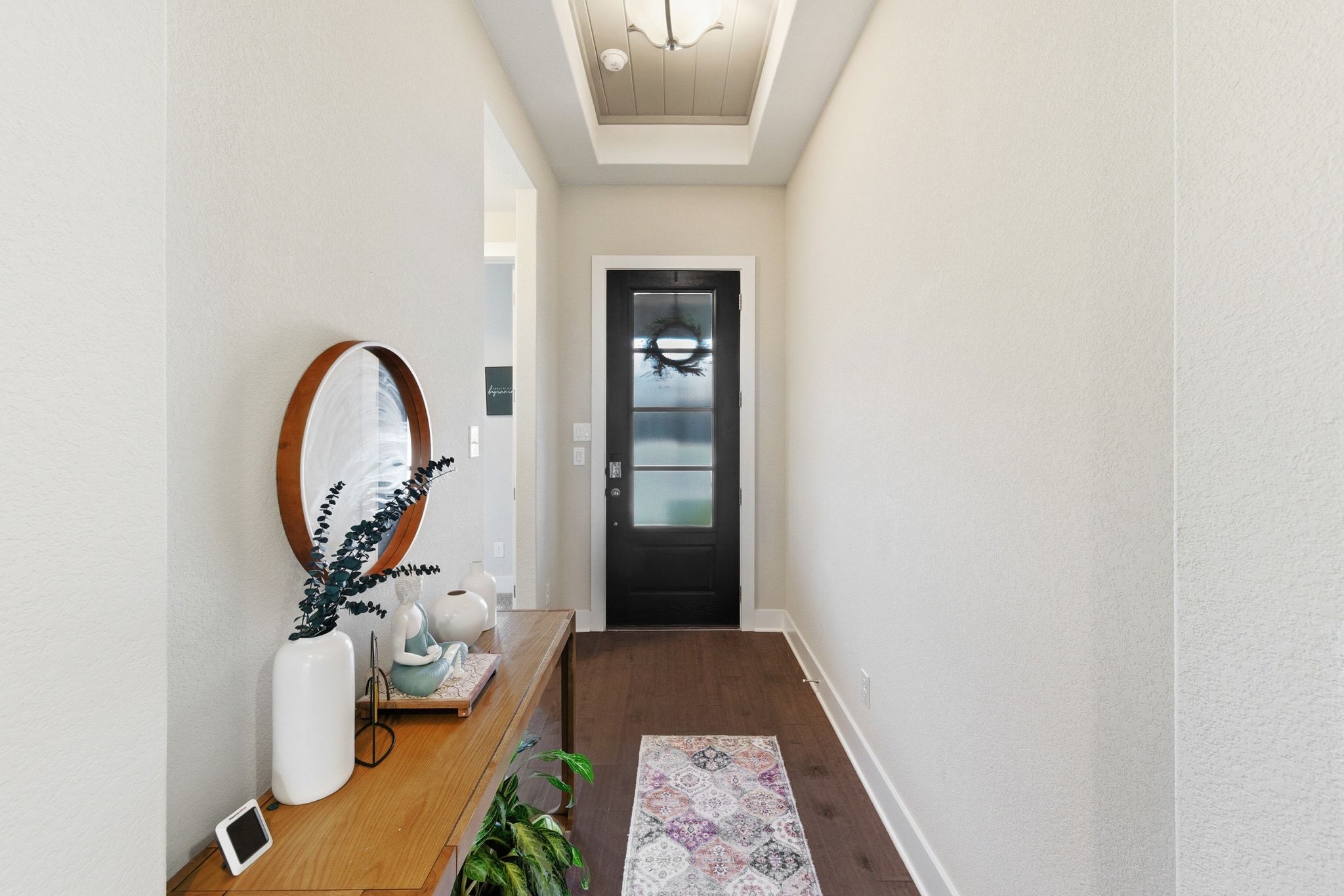 108 Leon Loop Liberty Hill, TX 78642 - Photo 4 of 39 Doorway with wood finished floors, a raised ceiling, and a textured wall