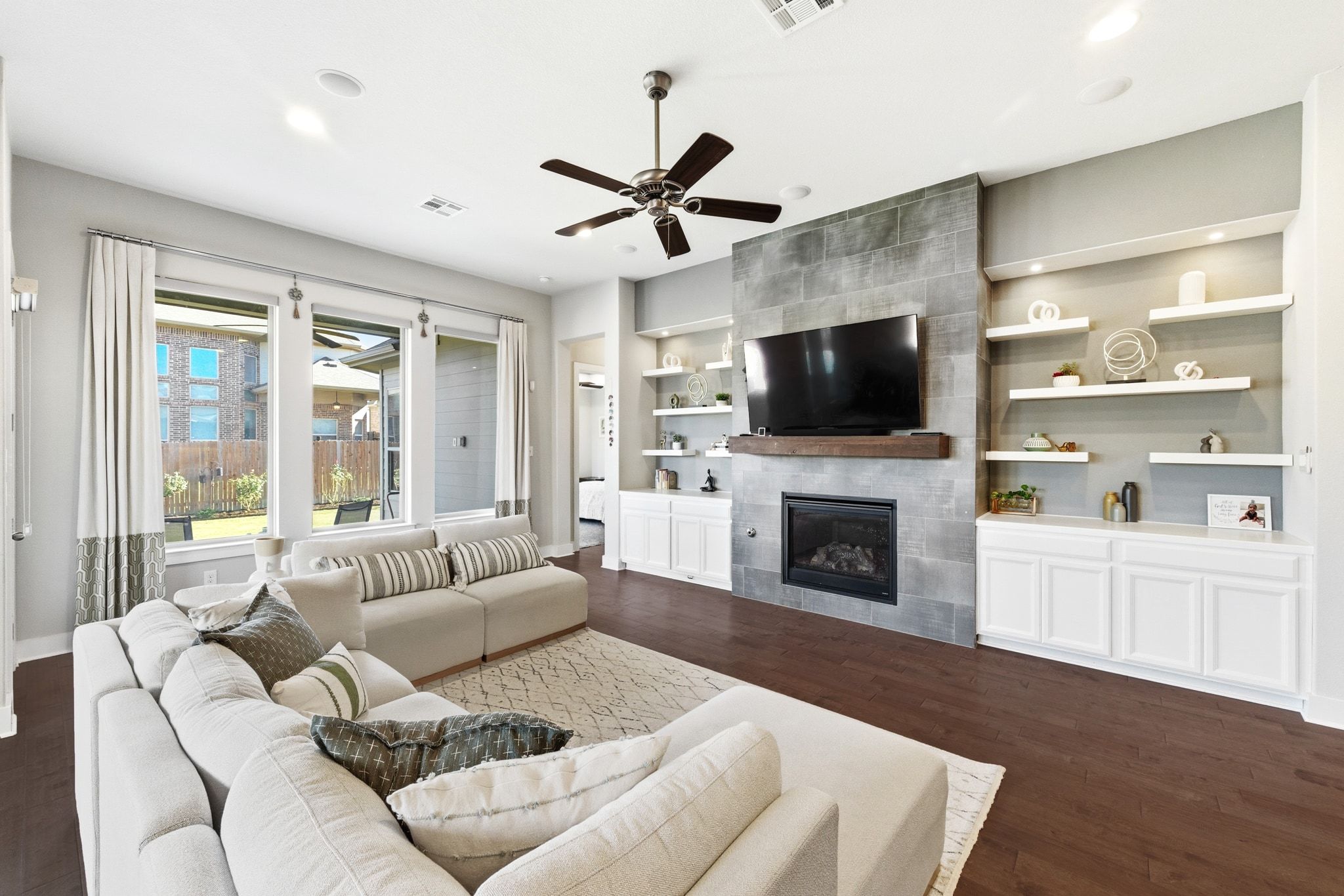 108 Leon Loop Liberty Hill, TX 78642 - Photo 8 of 39 Living room featuring a tiled fireplace, ceiling fan, built in shelves, dark wood-style flooring, and recessed lighting