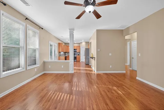 a view of an empty room with wooden floor and window