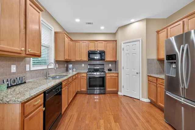 a kitchen with stainless steel appliances granite countertop a stove a sink and a refrigerator