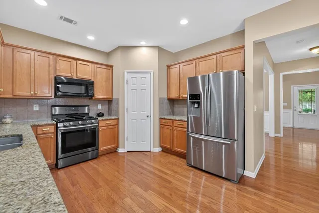 a kitchen with granite countertop a refrigerator and a stove top oven