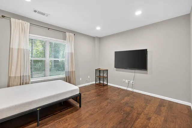a living room with a flat screen tv on dresser and a table
