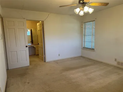 an empty room with windows and ceiling fan