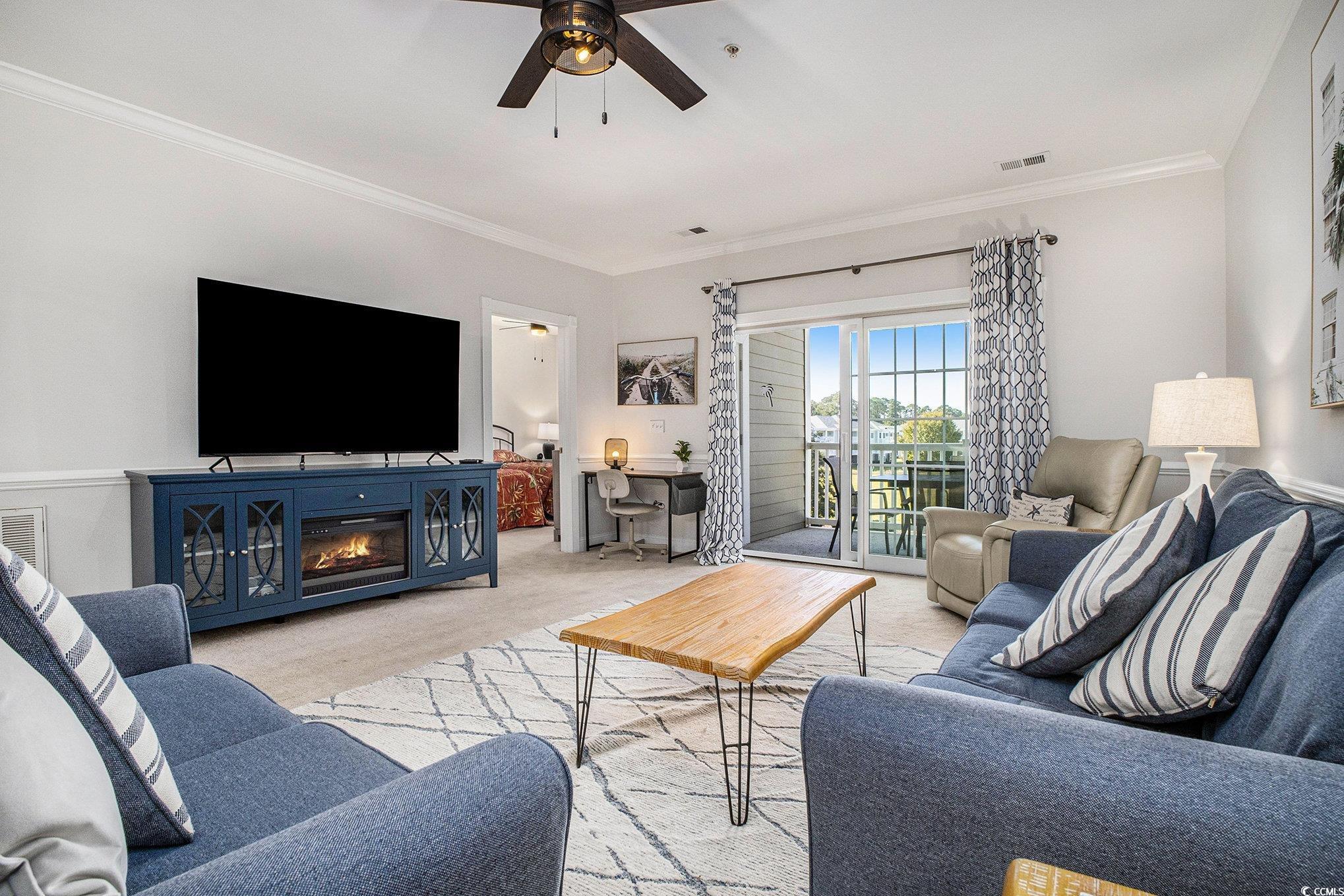 4894 Luster Leaf Circle, Unit 303 Myrtle Beach, SC 29577 - Photo 11 of 31 Carpeted living area with ornamental molding, ceiling fan, and a fireplace