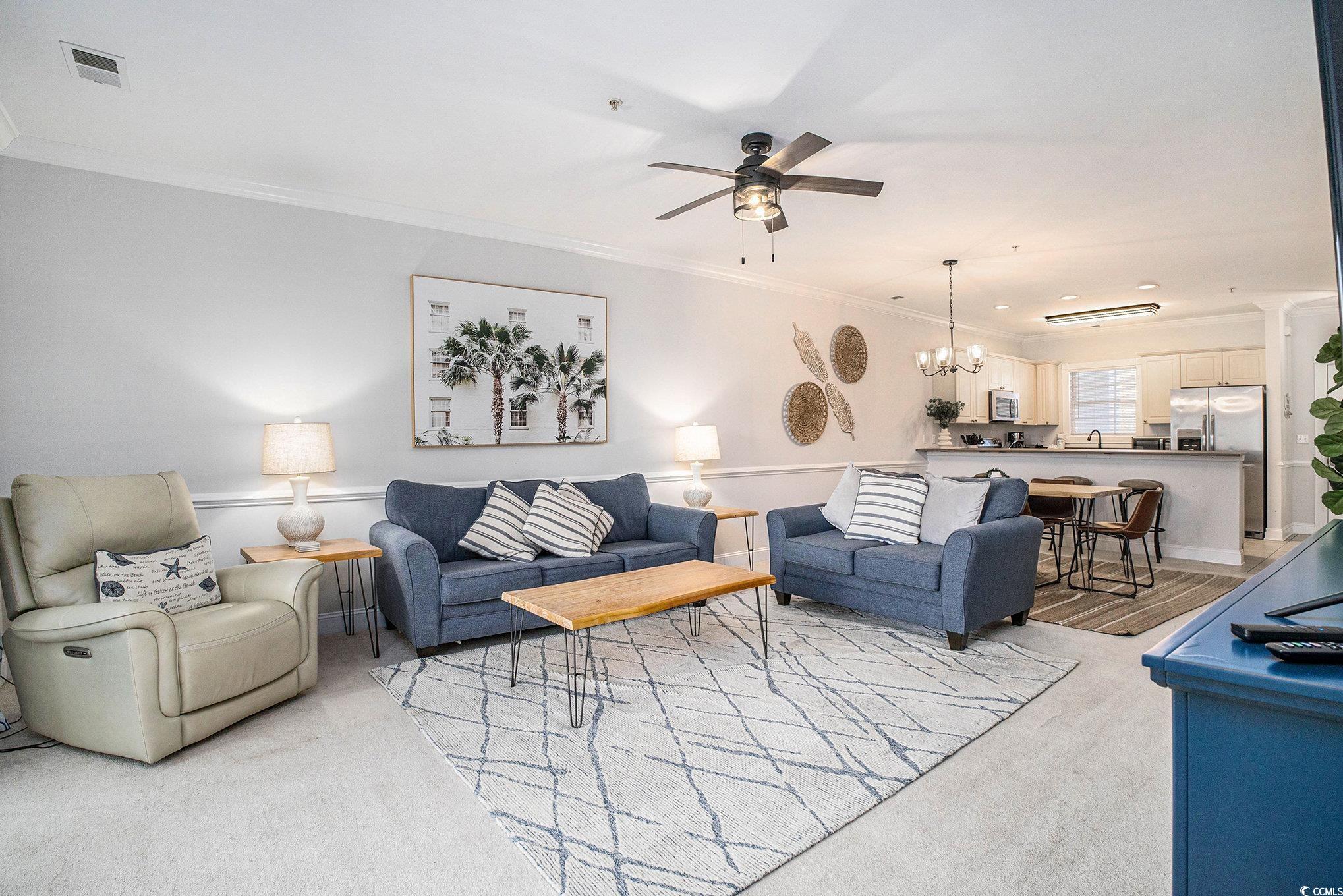 4894 Luster Leaf Circle, Unit 303 Myrtle Beach, SC 29577 - Photo 12 of 31 Living area featuring a chandelier, ornamental molding, ceiling fan, and light colored carpet