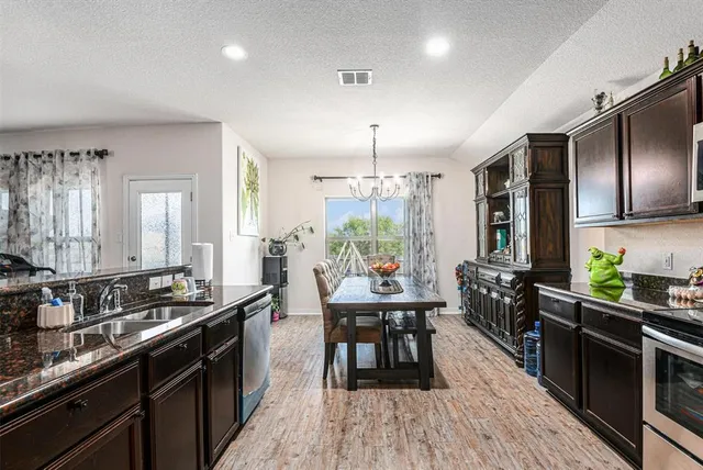 a kitchen with stainless steel appliances a kitchen island hardwood floor sink stove dining table and chairs