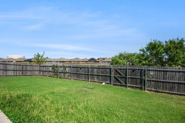 a view of a backyard with a garden and wooden fence