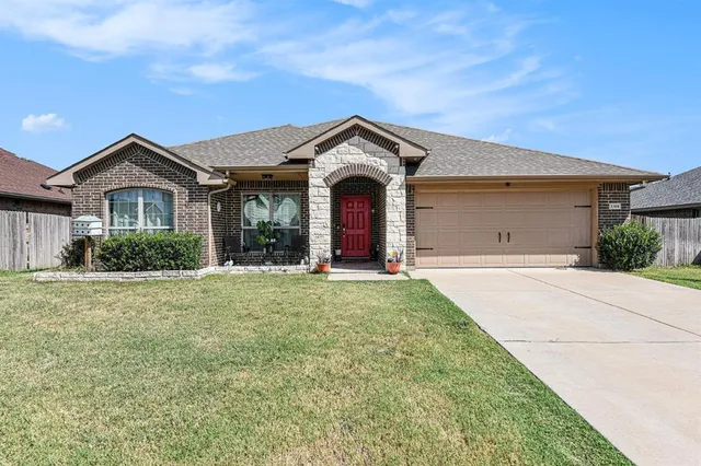 a view of a brick house with a big yard and large trees