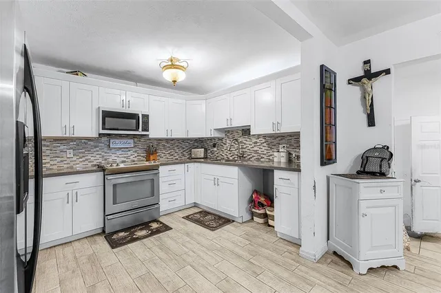 a kitchen with granite countertop a stove top oven a sink dishwasher and white cabinets with wooden floor