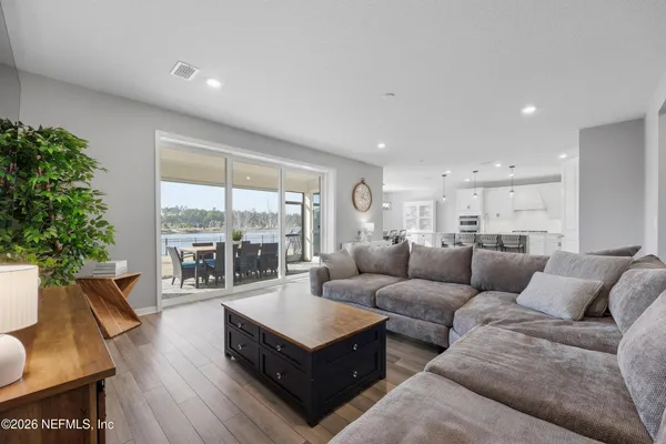 a kitchen with stainless steel appliances granite countertop a stove a refrigerator a kitchen island a sink and white cabinets with wooden floor