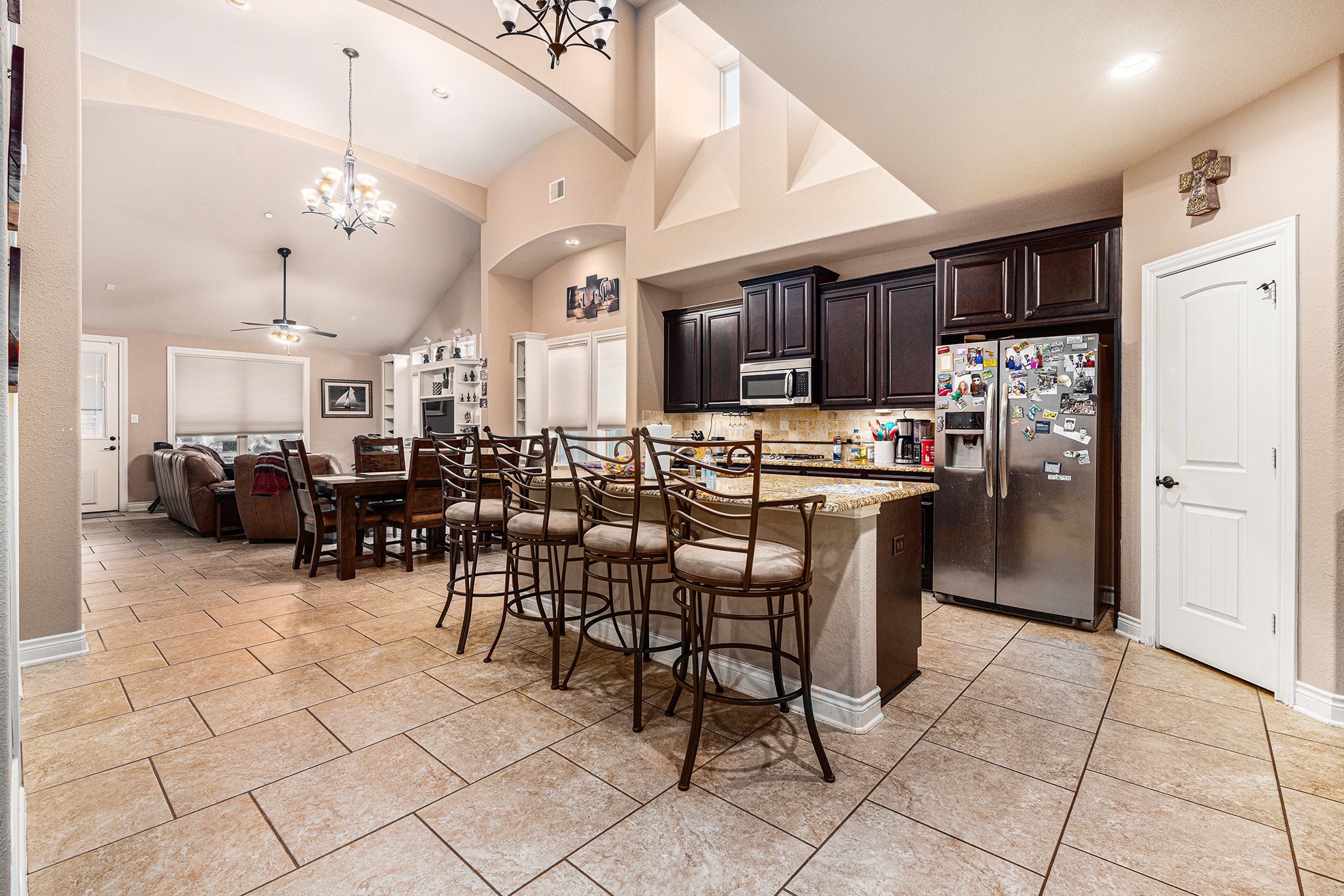 9039 Centennial Drive Conroe, TX 77384 - Photo 5 of 16 a kitchen with stainless steel appliances kitchen island granite countertop a refrigerator a stove a dining table and chairs with wooden floor