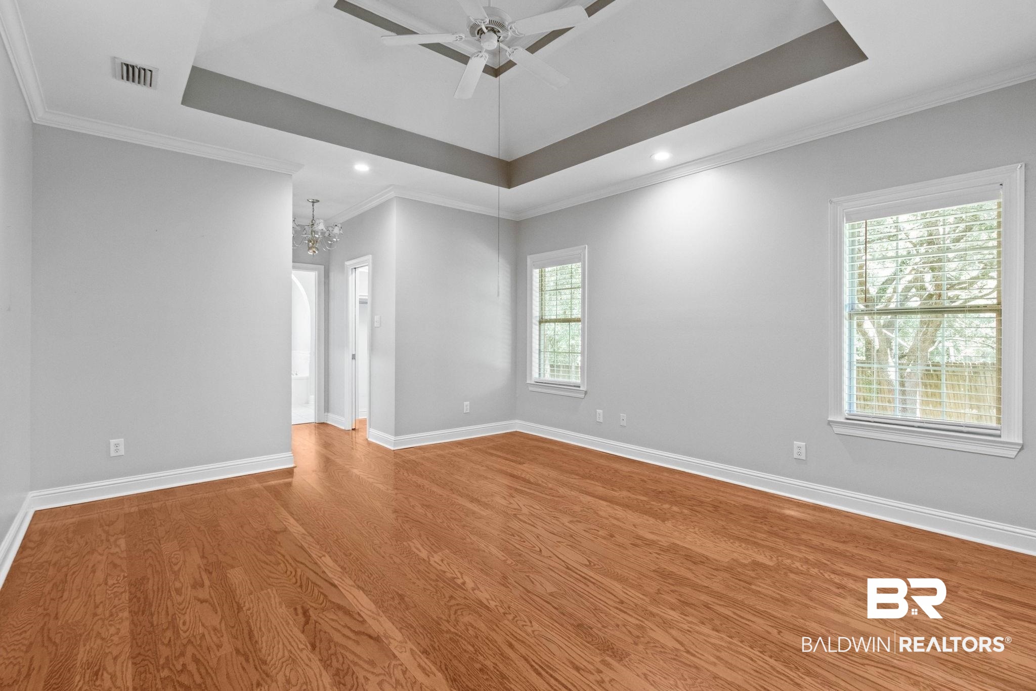 3176 Cedar Court Mobile, AL 36619 - Photo 14 of 33 Spacious room featuring wood-finish flooring, two windows with blinds, a tray ceiling with a ceiling fan, recessed lighting, and crown molding