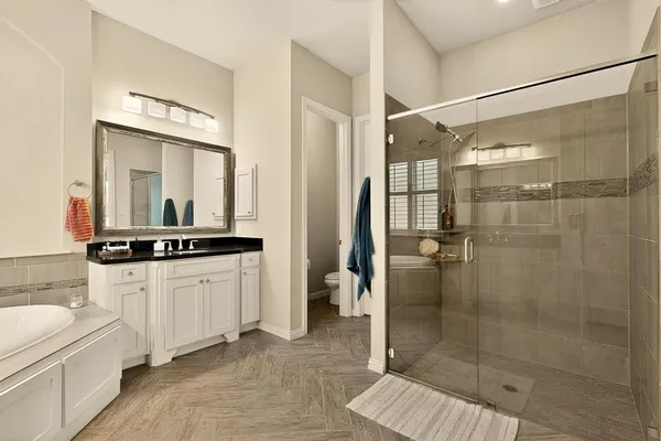 a bathroom with a granite countertop sink a mirror and a shower