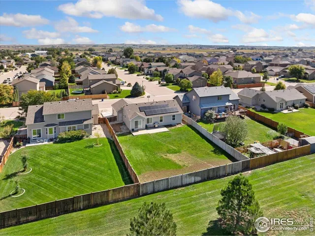 an aerial view of a residential houses with outdoor space and trees