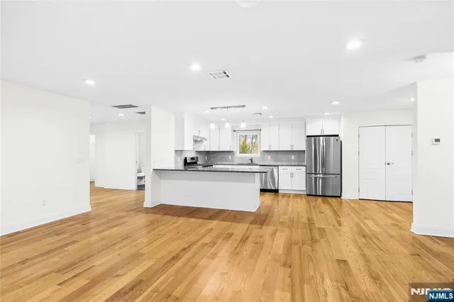 a large kitchen with kitchen island a stove a refrigerator a sink dishwasher with a oven and white cabinets