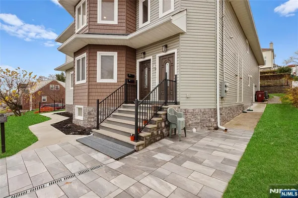 a view of a white house with a small yard and a large tree