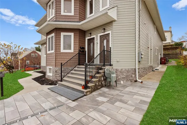 a view of a white house with a small yard and a large tree