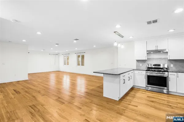 a large kitchen with stainless steel appliances granite countertop a stove a sink and a refrigerator