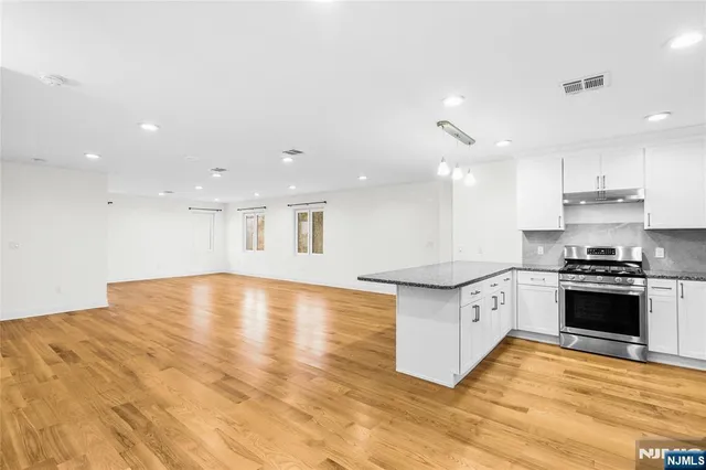 a large kitchen with stainless steel appliances granite countertop a stove a sink and a refrigerator