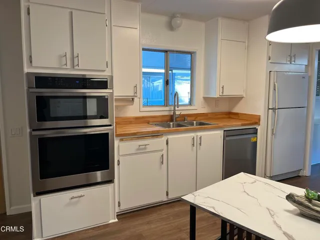 a kitchen with granite countertop a refrigerator stove and white cabinets
