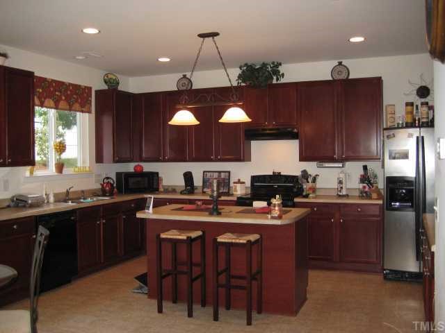 148 Solheim Lane Raleigh, NC 27603 - Photo 4 of 12 a kitchen with kitchen island granite countertop a sink counter top space appliances and cabinets