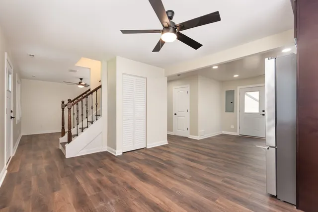 a view of an empty room with wooden floor and a ceiling fan