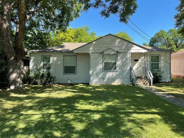 a backyard of a house with table and chairs under an umbrella