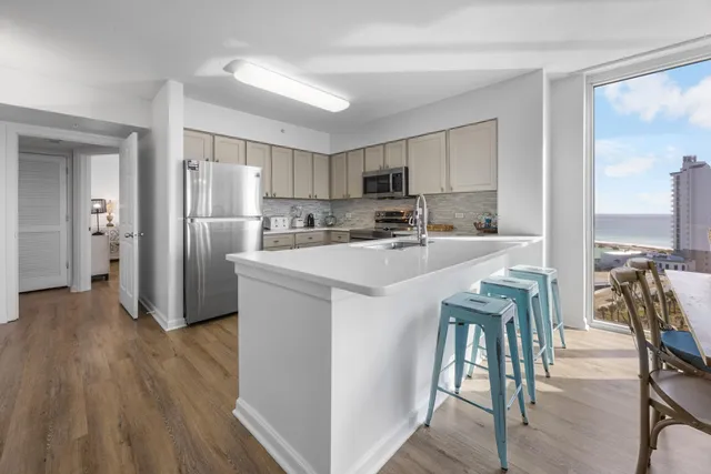 a kitchen with stainless steel appliances a refrigerator a stove a sink dishwasher and white cabinets with wooden floor