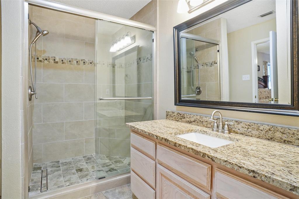 1116 Shadow Ridge Drive Azle, TX 76020 - Photo 16 of 27 a bathroom with a granite countertop sink a mirror a glass door a shower and a mirror