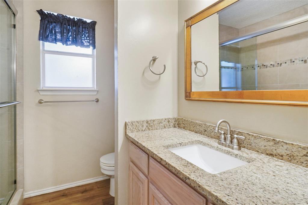 1116 Shadow Ridge Drive Azle, TX 76020 - Photo 20 of 27 a bathroom with a granite countertop sink a toilet and a mirror