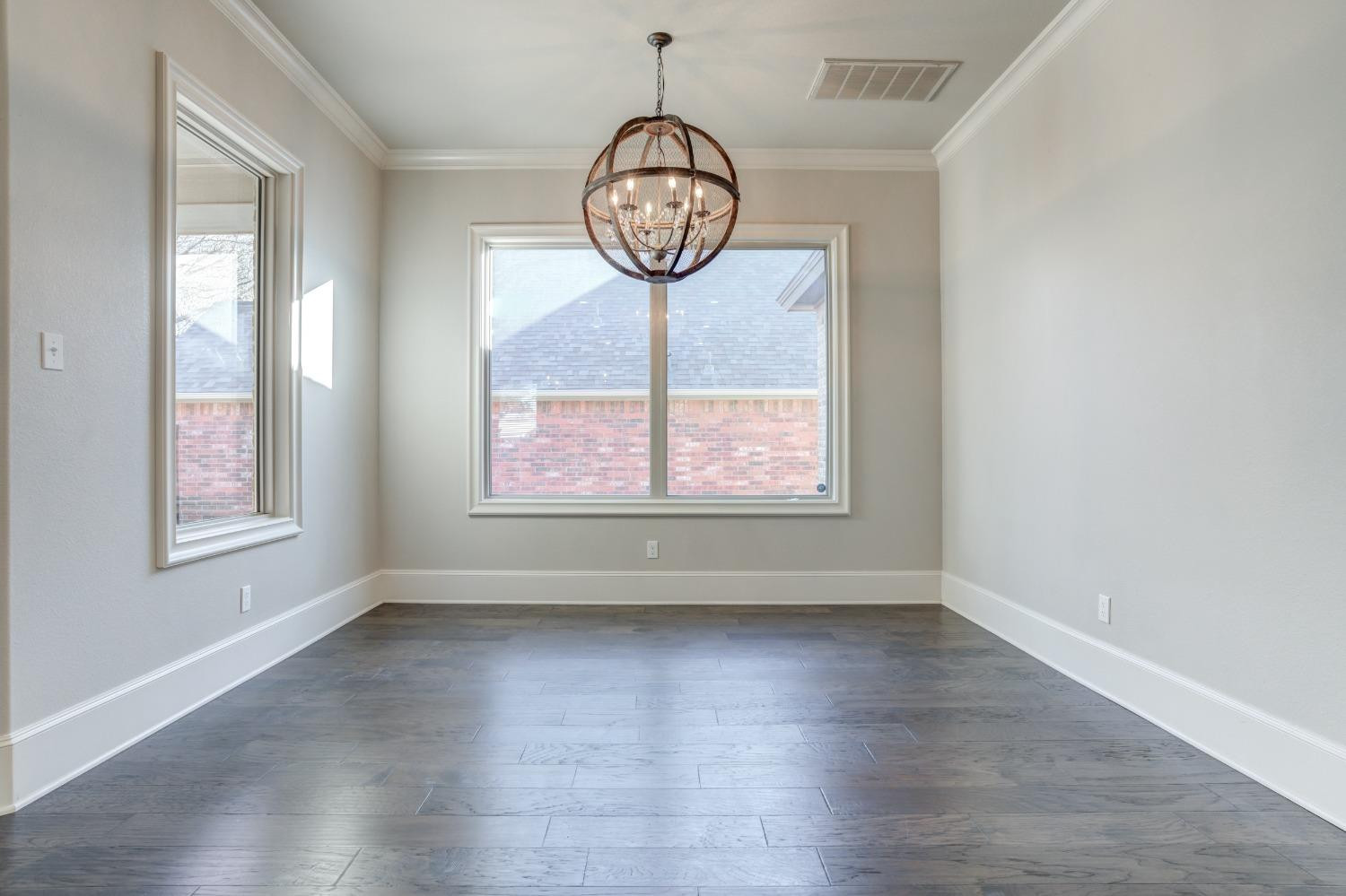 402 Topeka Avenue Lubbock, TX 79416 - Photo 18 of 41 an empty room with wooden floor a chandelier and windows