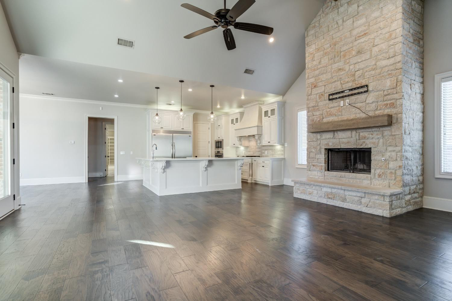 402 Topeka Avenue Lubbock, TX 79416 - Photo 5 of 41 a view of an empty room and kitchen with fireplace wooden floor