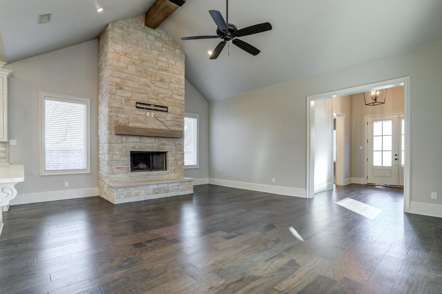 402 Topeka Avenue Lubbock, TX 79416 - Photo 7 of 41 an empty room with wooden floor a fireplace and windows