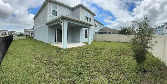 a view of a house with a big yard and large trees