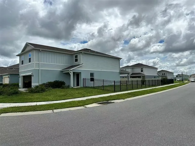 a view of a white house with a big yard and plants