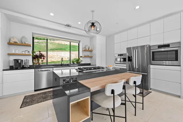 a kitchen with stainless steel appliances granite countertop a stove a refrigerator a oven a sink with a dining table and chairs