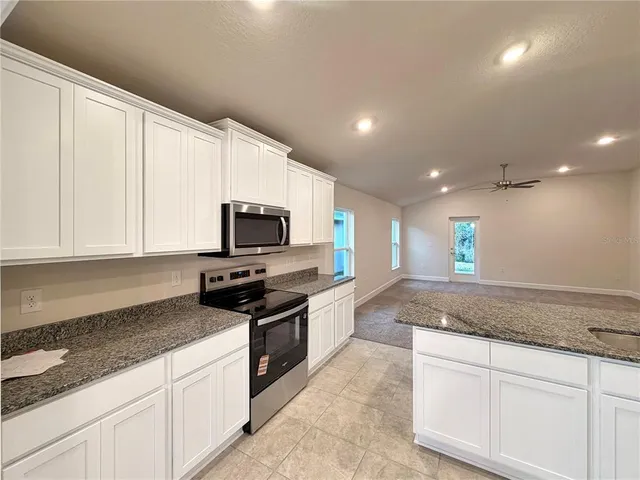 a kitchen with granite countertop a sink stainless steel appliances and white cabinets
