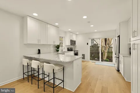 a large white kitchen with stainless steel appliances granite countertop a stove and a refrigerator