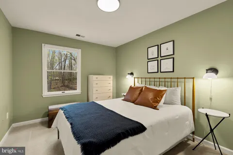 a bedroom with a bed a painting on the wall and a window