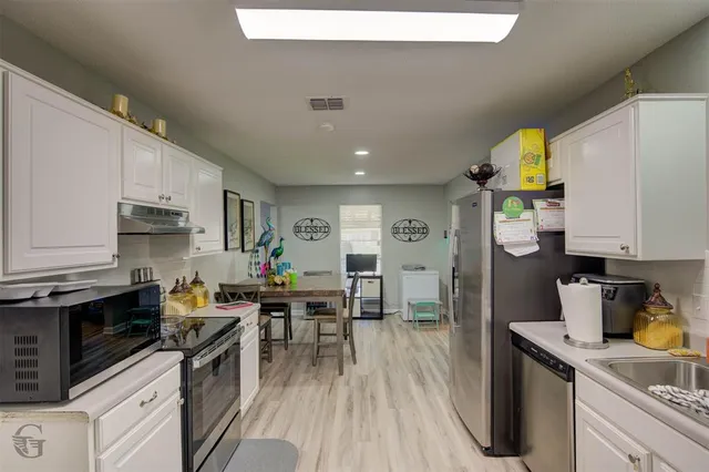 a kitchen that has a lot of cabinets a sink and appliances in it
