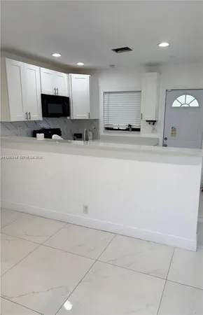 a view of kitchen with granite countertop lots of white cabinets