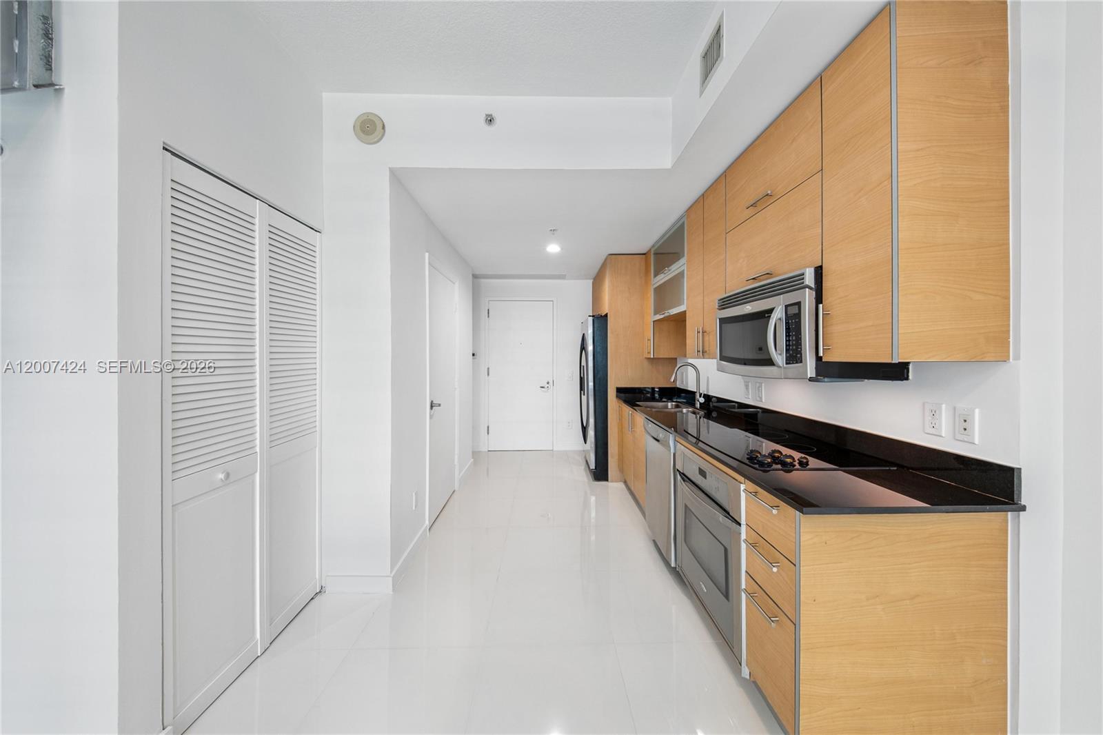 60 Southwest 13th Street, Unit 2420 Miami, FL 33130 - Photo 9 of 30 a kitchen with stainless steel appliances a stove a microwave and a refrigerator