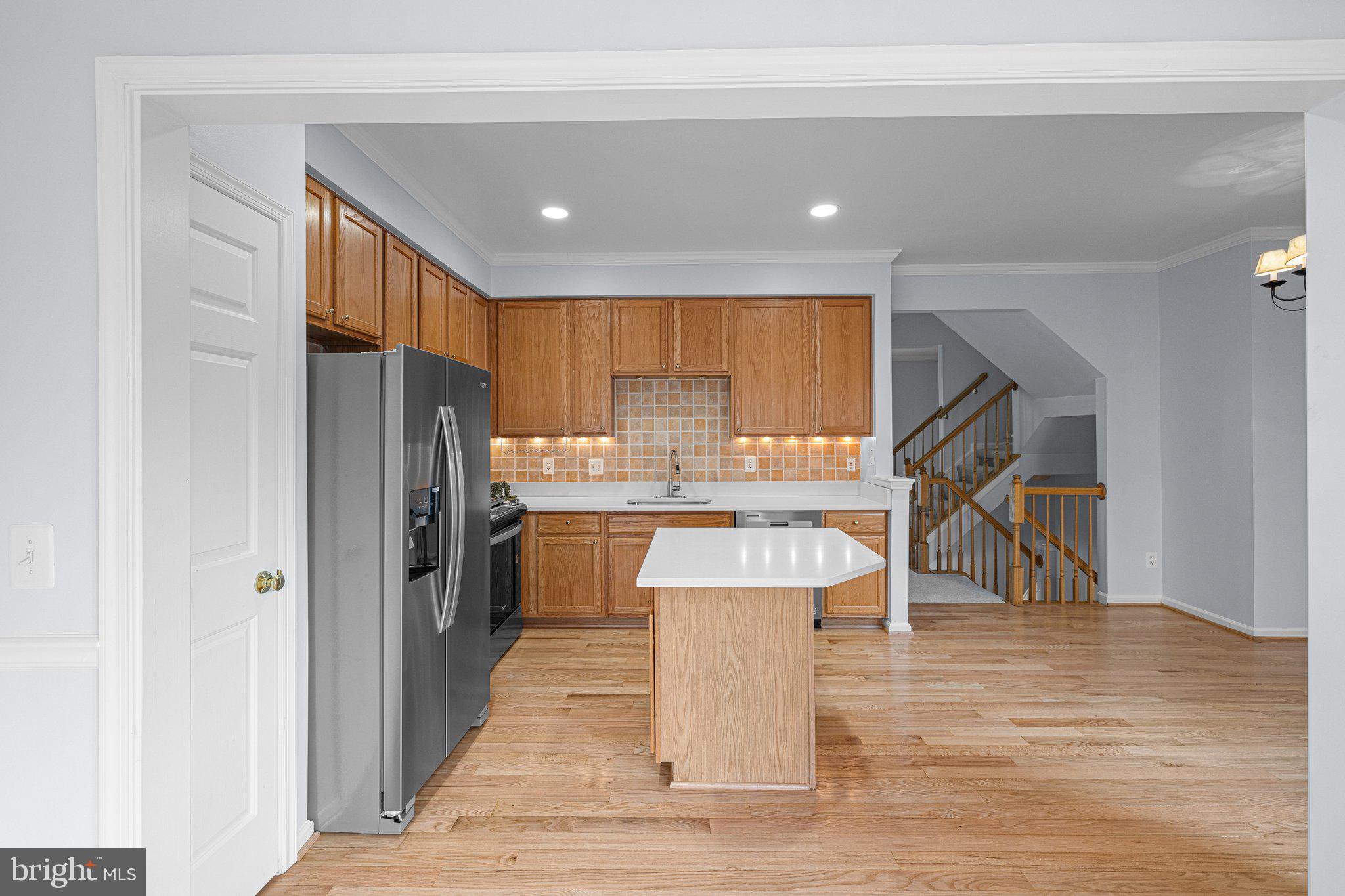 43002 Center Street Chantilly, VA 20152 - Photo 10 of 35 a kitchen with stainless steel appliances kitchen island granite countertop a refrigerator a stove a sink and a dining table with wooden floor