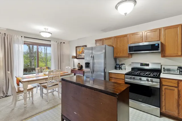 a kitchen with a stove a sink dishwasher a refrigerator and a dining table with wooden cabinet