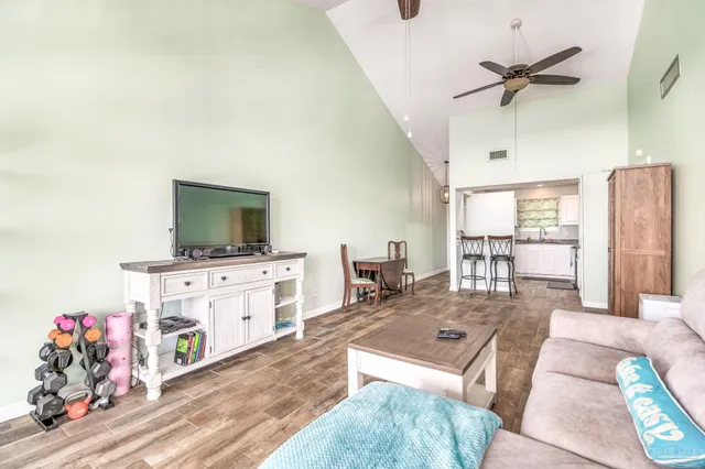 a living room with furniture a flat screen tv and a refrigerator