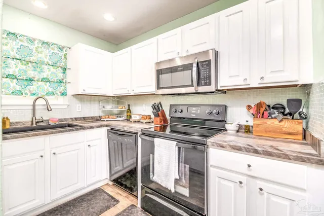 a kitchen with granite countertop white cabinets and white appliances